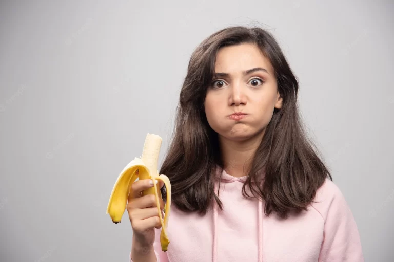young-woman-eating-banana-gray-wall_114579-47208 (1)